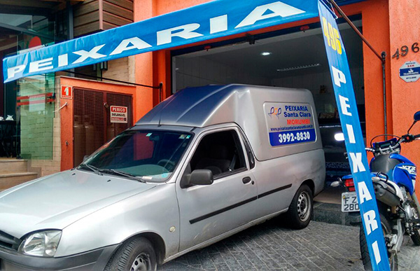 Foto da fachada da peixaria, com o carro de entrega estacionado na frente.