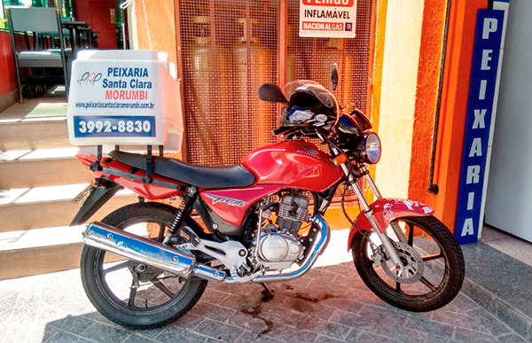 Foto da moto de entrega, com baú para transporte dos produtos.